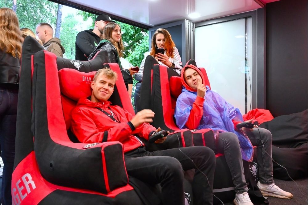 Účastníci s ovládačmi na červeno-čiernych stoličkách BAGER na Rap Stacja 2025