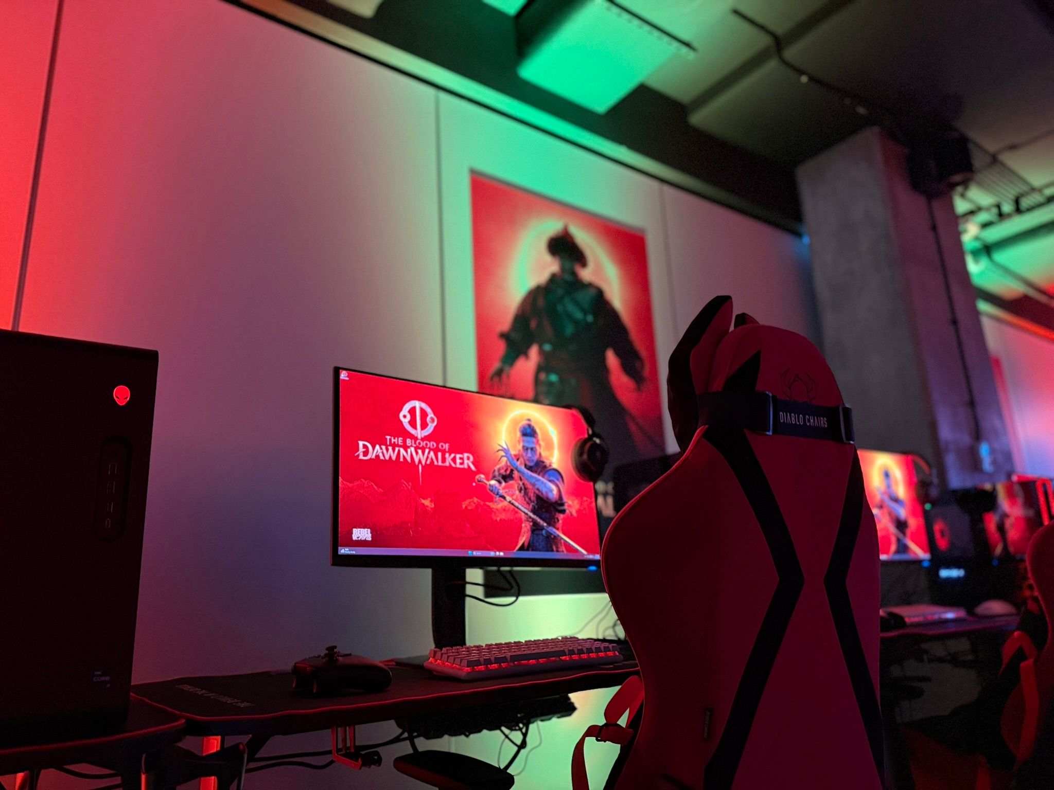 The Blood of Dawnwalker na monitore a stolička v červeno-zelenom osvetlení