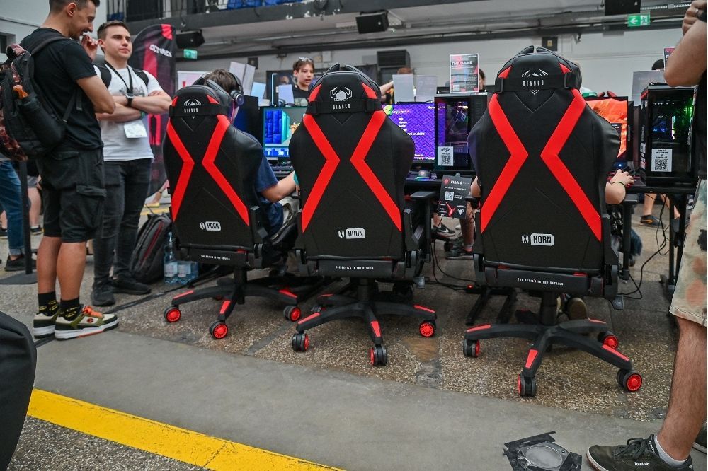 Rad čierno-červených stoličiek pri herných stanovištiach na Pixel Heaven Forward 2025