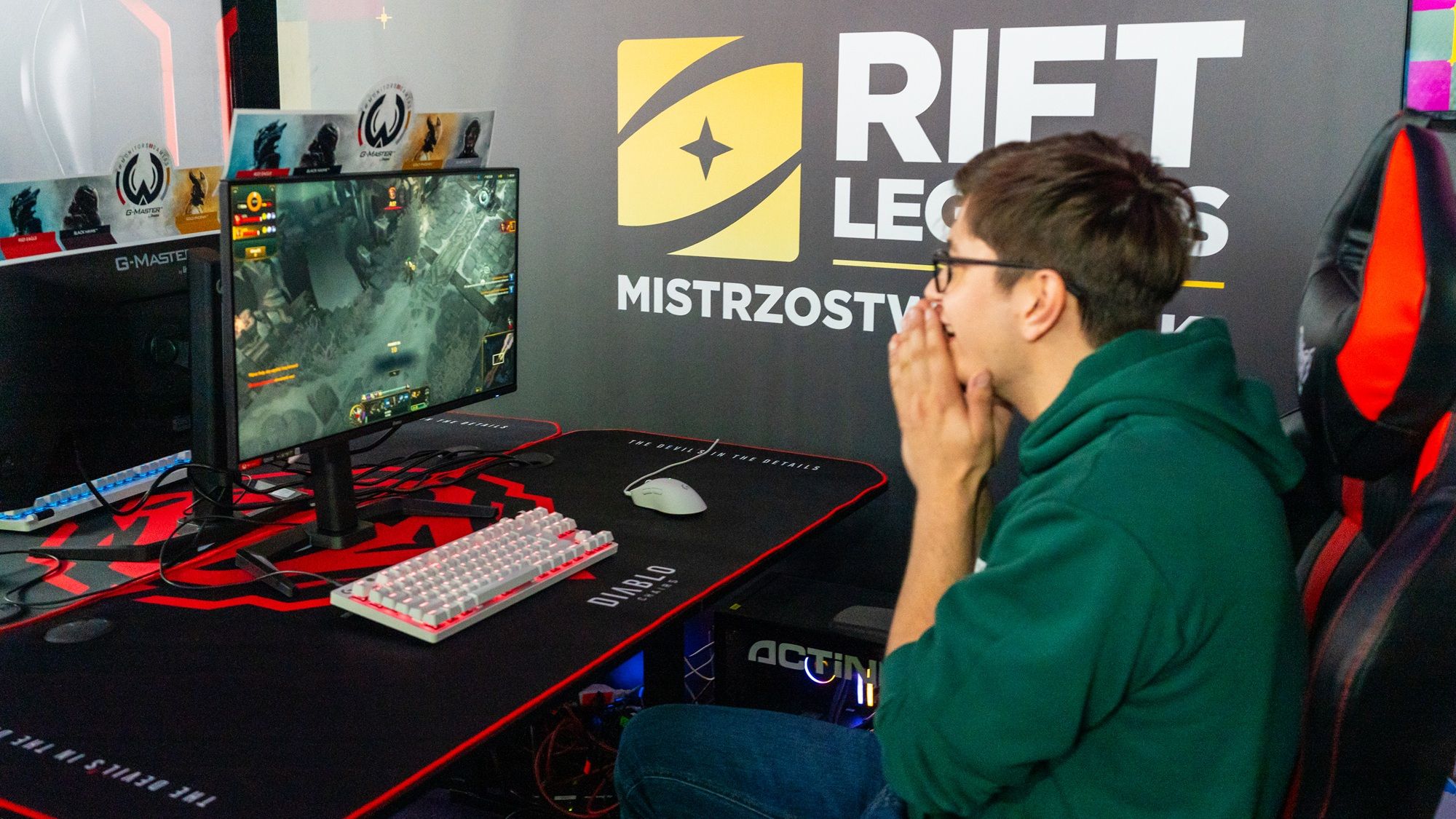 Účastník v zelenej mikine pri počítači v zóne Rift Legends
