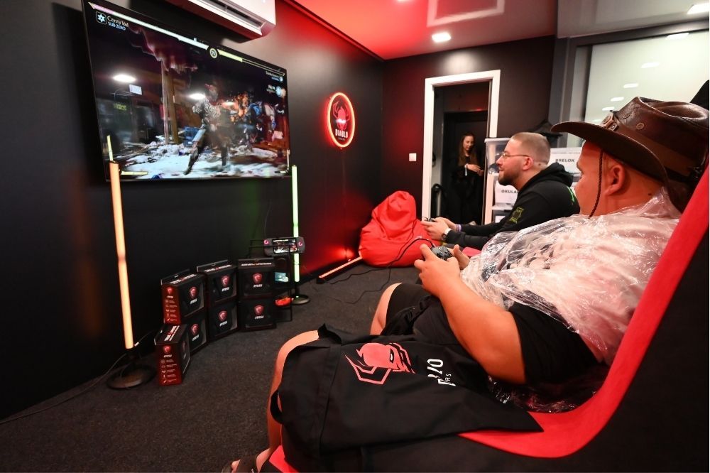Účastníci hrajú na konzole pred veľkou obrazovkou na Rap Stacja 2025