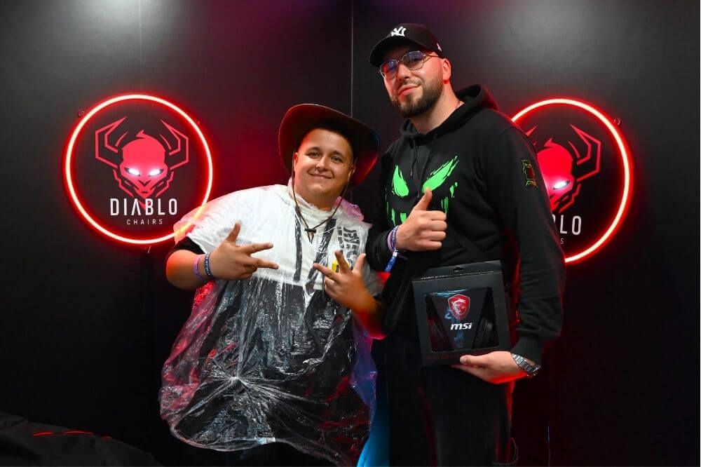 Dvaja návštevníci pózujú pred neónovým logom Diablo Chairs na Rap Stacja